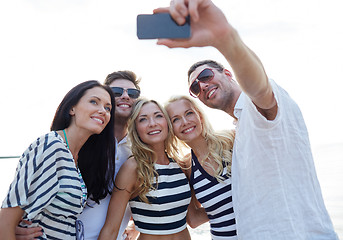 Image showing happy friends on beach and taking selfie