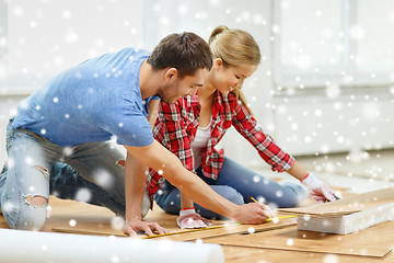 Image showing smiling couple measuring wood flooring