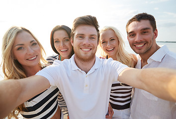 Image showing happy friends on beach and taking selfie