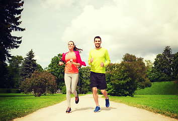 Image showing smiling couple with earphones running outdoors