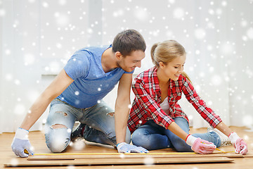 Image showing smiling couple measuring wood flooring