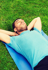 Image showing smiling man lying on mat outdoors