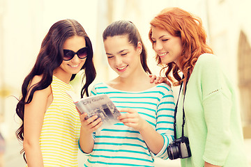 Image showing smiling teenage girls with city guide and camera