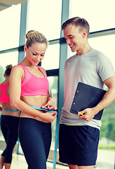 Image showing smiling young woman with personal trainer in gym