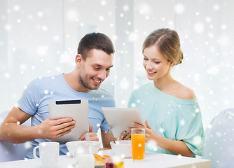 Image showing smiling couple with tablet pc having breakfast