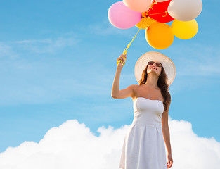 Image showing smiling young woman in sunglasses with balloons