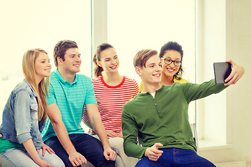 Image showing smiling students making picture with tablet pc