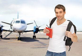 Image showing smiling student with backpack and book at airport