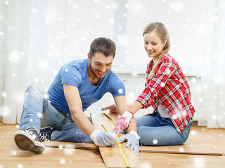 Image showing smiling couple measuring wood flooring