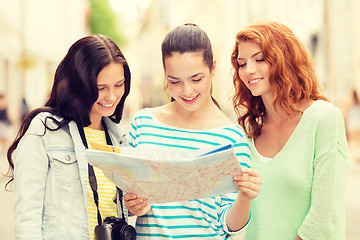 Image showing smiling teenage girls with map and camera