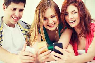 Image showing three smiling students with smartphone at school