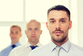 Image showing serious businessman in office with team on back