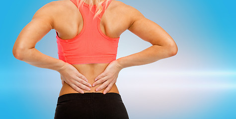 Image showing close up of sporty woman touching her back