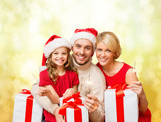 Image showing smiling family holding gift boxes and sparkles