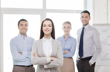 Image showing smiling businesswoman in office with team on back