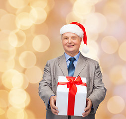 Image showing smiling man in suit and santa helper hat with gift