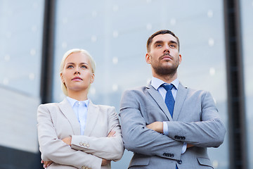 Image showing serious businessmen standing over office building