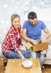 Image showing smiling couple opening cardboard box with dishes