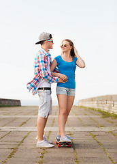 Image showing smiling couple with skateboard outdoors