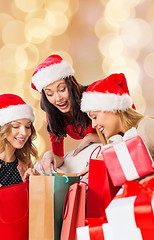 Image showing smiling young women in santa hats with gifts