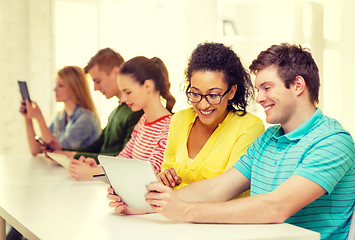 Image showing smiling students looking at tablet pc at school