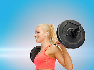 Image showing smiling sporty woman exercising with barbell