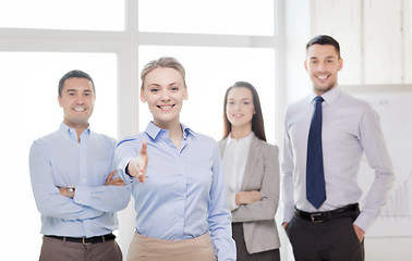 Image showing smiling businesswoman in office with team on back