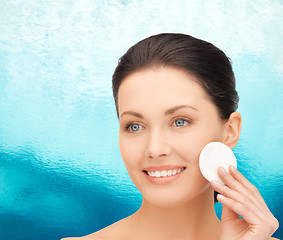 Image showing smiling woman cleaning face skin with cotton pad