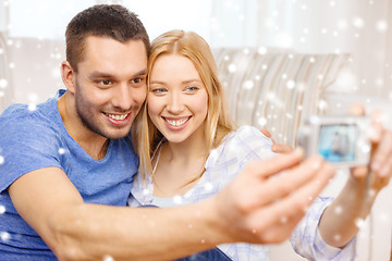 Image showing smiling couple taking picture with digital camera