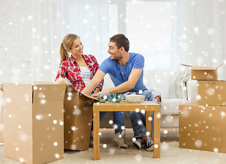 Image showing smiling couple opening cardboard box with dishes