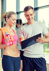 Image showing smiling young woman with personal trainer in gym