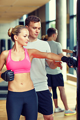 Image showing smiling woman with personal trainer boxing in gym