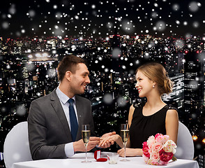 Image showing smiling couple with red gift box at restaurant