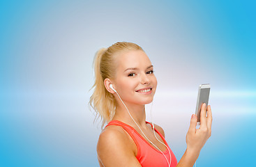 Image showing smiling sporty woman with smartphone and earphones