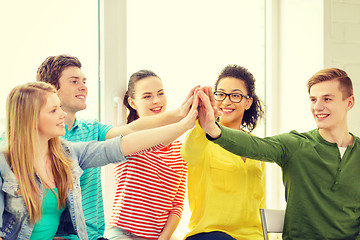 Image showing smiling students making high five gesture sitting