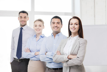 Image showing smiling businesswoman in office with team on back