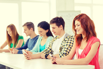 Image showing smiling students with smartphones at school