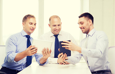 Image showing three smiling businessmen with tablet pc in office