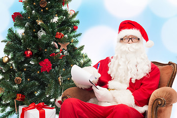 Image showing man in costume of santa claus with notepad