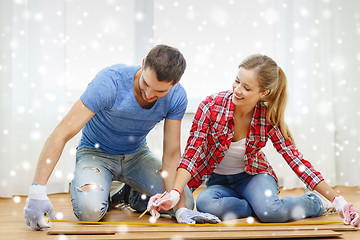 Image showing smiling couple measuring wood flooring