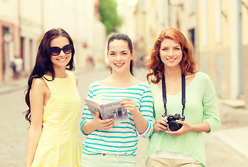 Image showing smiling teenage girls with city guide and camera