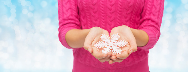 Image showing close up of woman in sweater holding snowflake