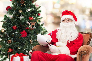 Image showing man in costume of santa claus with notepad