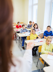 Image showing group of school kids raising hands in classroom