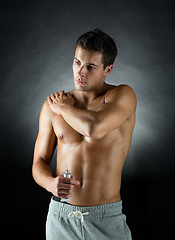 Image showing young male bodybuilder applying pain relief gel