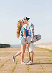 Image showing couple with skateboard kissing outdoors