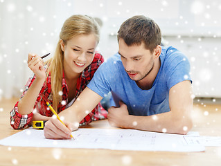 Image showing smiling couple with  blueprint at home