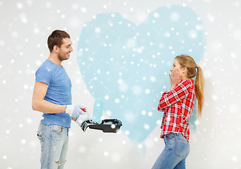 Image showing smiling couple painting big heart on wall