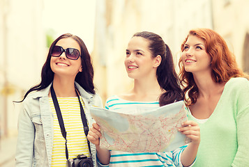 Image showing smiling teenage girls with map and camera