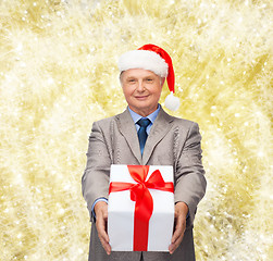 Image showing smiling man in suit and santa helper hat with gift